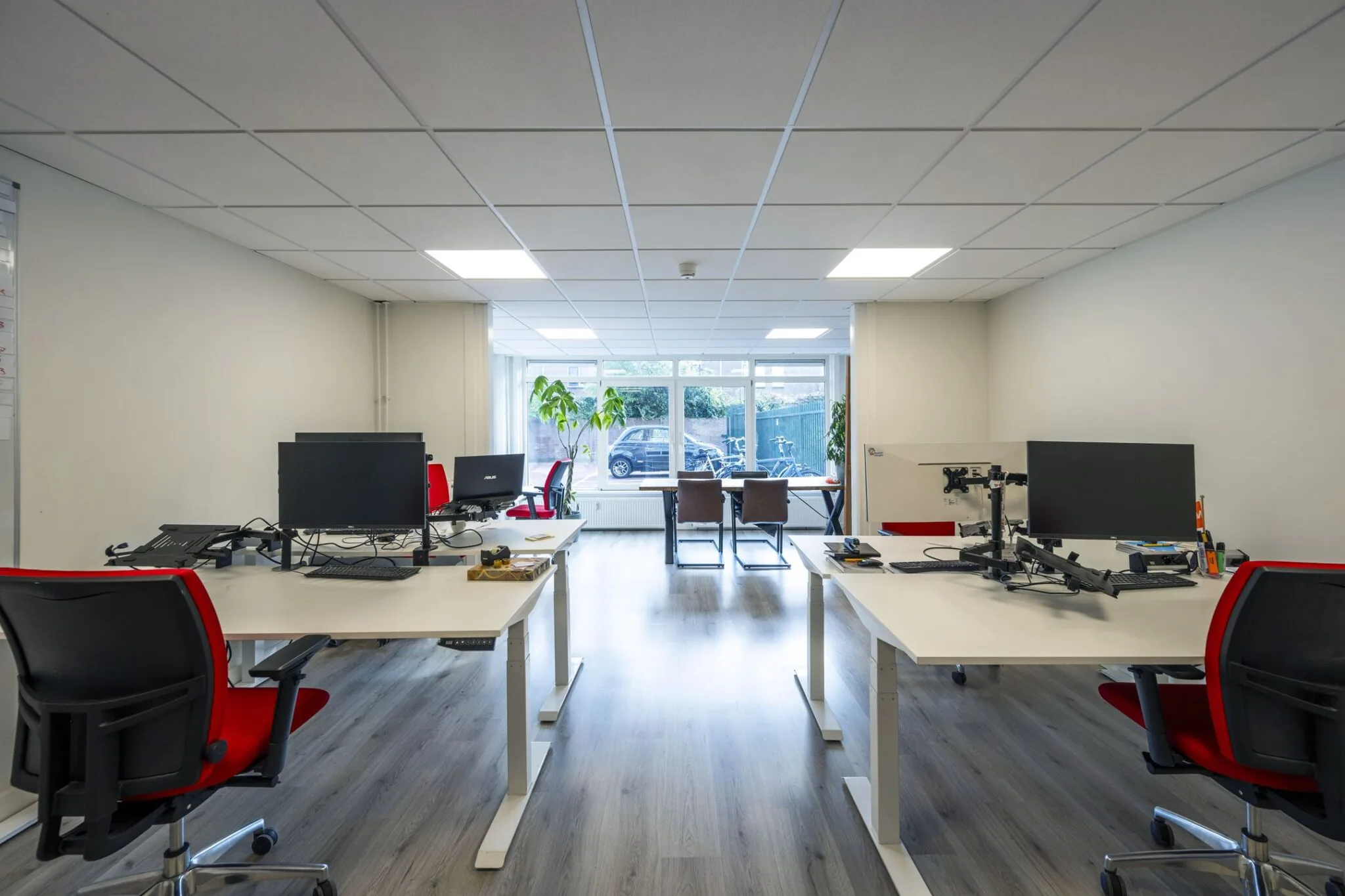 Moderne kantoorruimte aan de Nieuwe Gracht 45-47 in Haarlem met werkplekken, bureaustoelen en grote ramen.