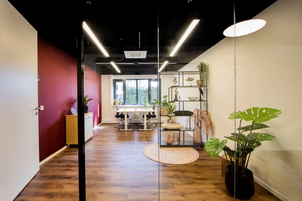 Moderne en stijlvolle kantoorruimte aan de Pelmolenlaan 16 in Woerden met houten vloer, glazen wand en decoratieve planten.