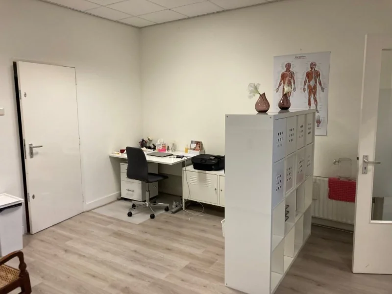 Kantoorruimte met werkplek, opbergkast en anatomische poster in het Sweelinckplein 9-21 in Den Haag.