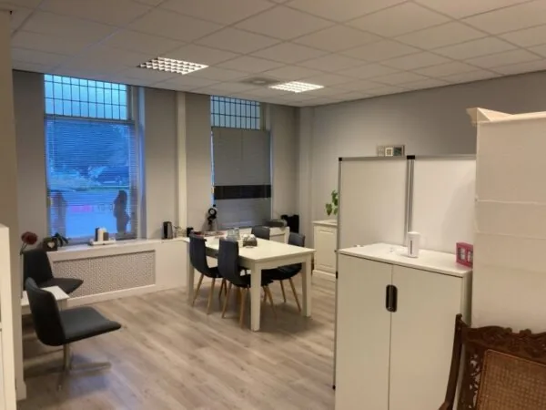 Moderne kantoorruimte aan het Sweelinckplein 9-21 in Den Haag met een vergadertafel, stoelen en kasten.