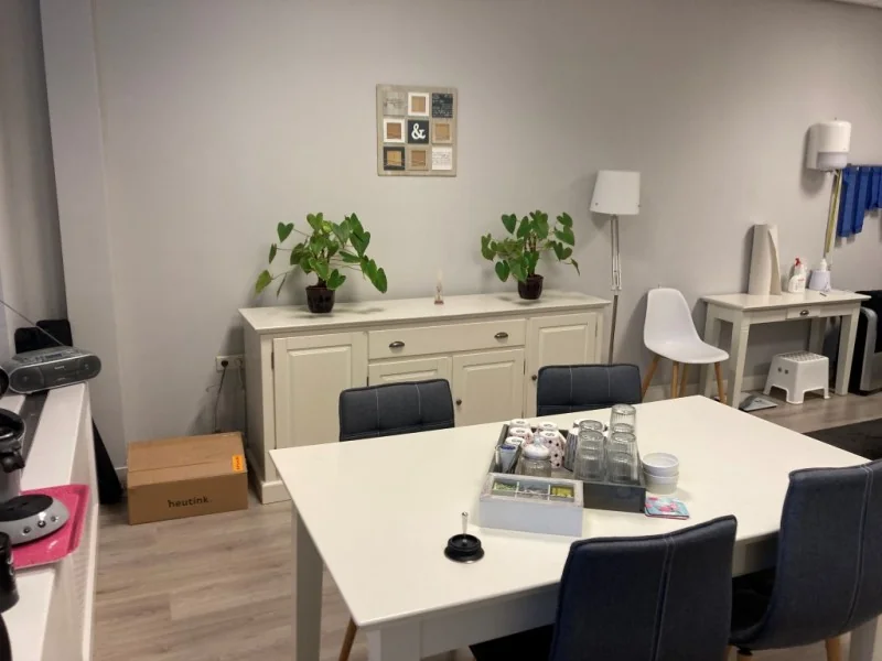 Moderne kantoorruimte aan het Sweelinckplein in Den Haag met een witte vergadertafel, donkergrijze stoelen en een gezellige inrichting.