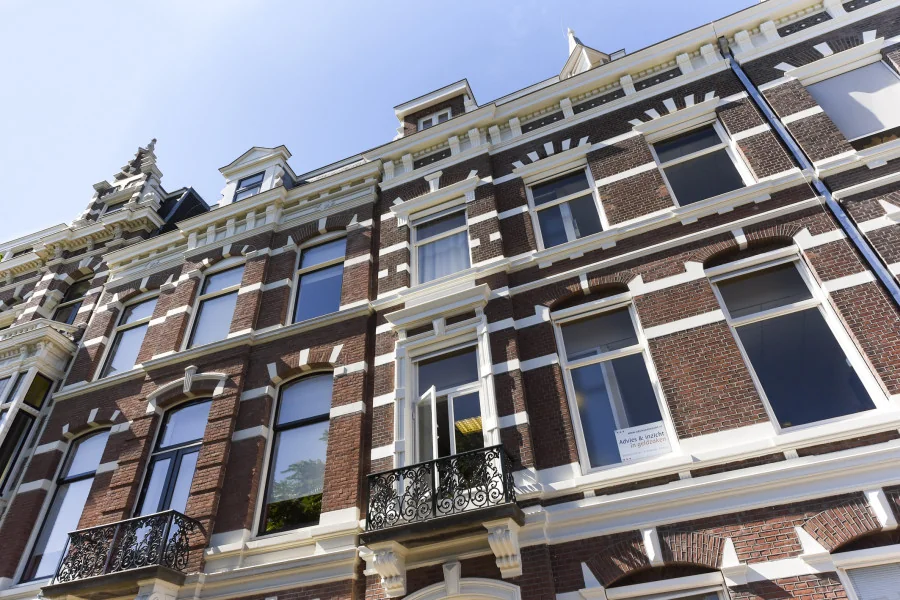 Voorgevel van een klassiek kantoorpand aan het Sweelinckplein 9-21 in Den Haag met grote ramen en smeedijzeren balkon.