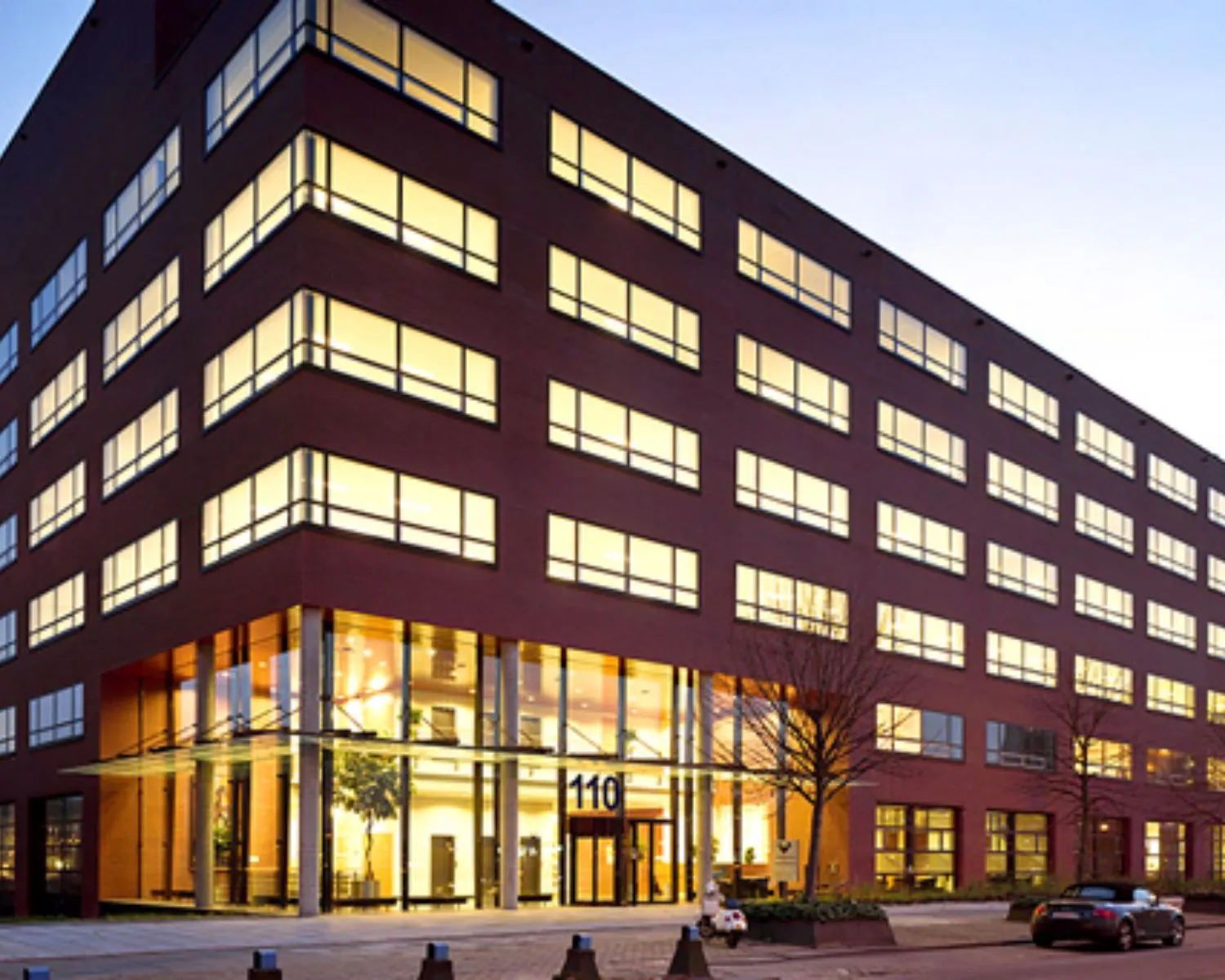 Modern kantoorgebouw aan de Teleportboulevard 110 in Amsterdam bij schemering.