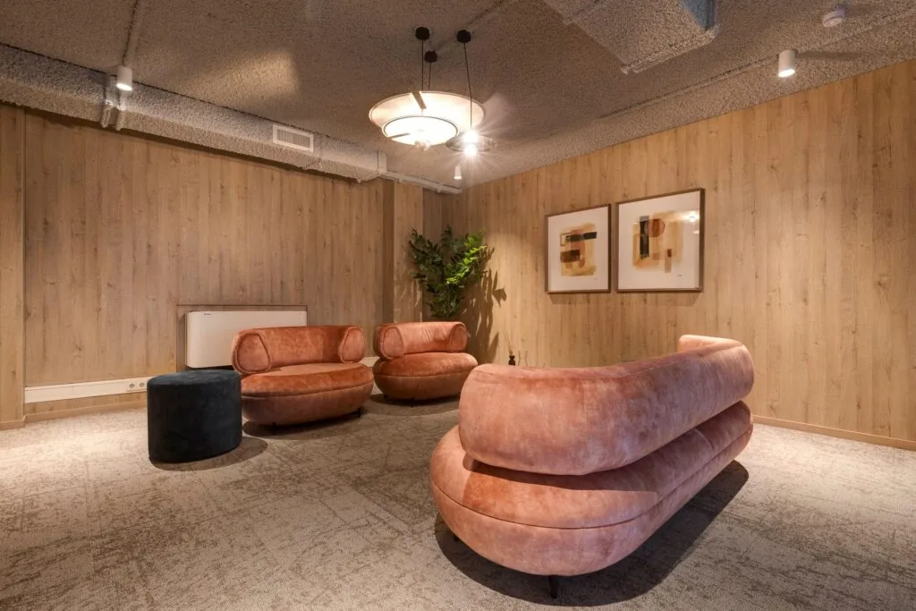 Stijlvol ingerichte loungehoek in een kantoorruimte aan de Vanadiumweg 11 in Amersfoort met fluwelen zitmeubels en houten wandafwerking.