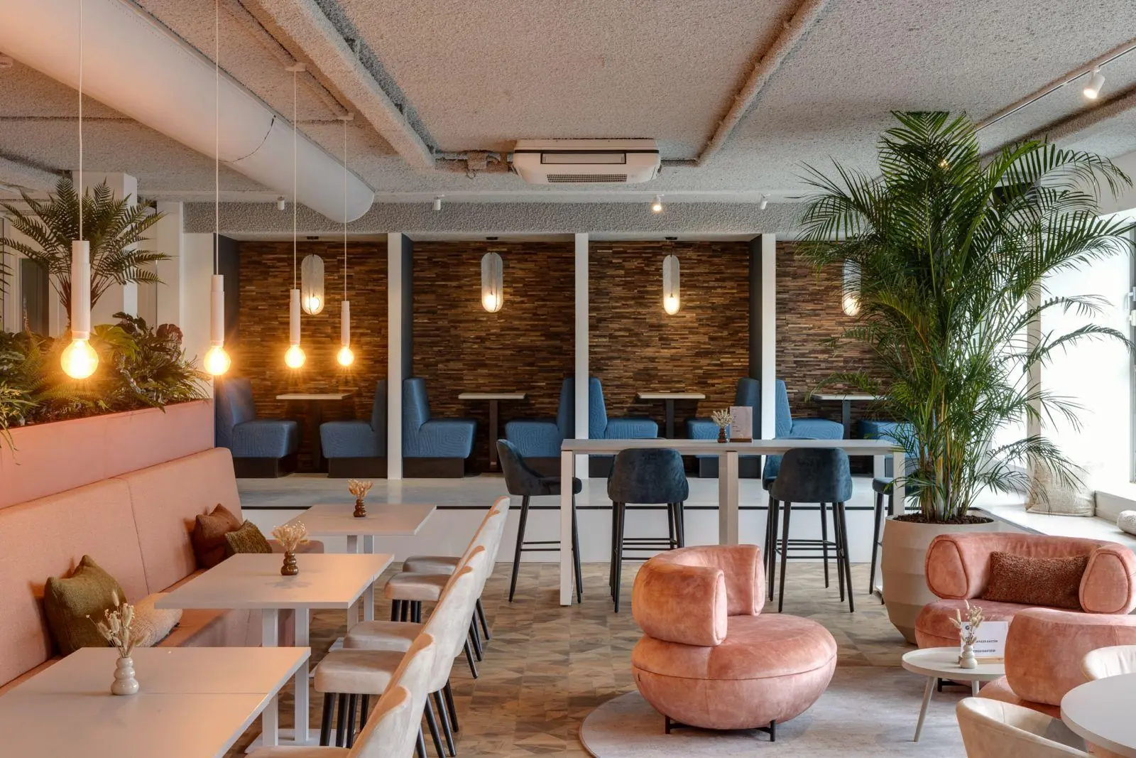 Modern ingerichte kantoorruimte aan de Vanadiumweg 11 in Amersfoort met stijlvolle zitplekken, hanglampen en grote kamerplanten.