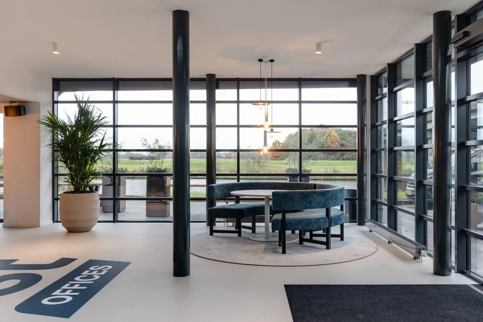 Moderne kantoorruimte aan de Vanadiumweg 11 in Amersfoort met glazen wanden, ronde zithoek en uitzicht op groen landschap.