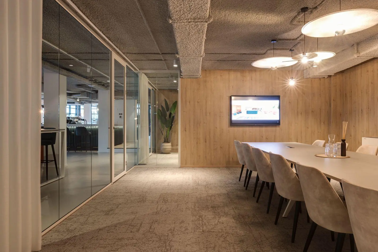 Moderne vergaderruimte aan de Vanadiumweg 11 in Amersfoort met sfeervolle verlichting, een lange tafel en glazen wanden.