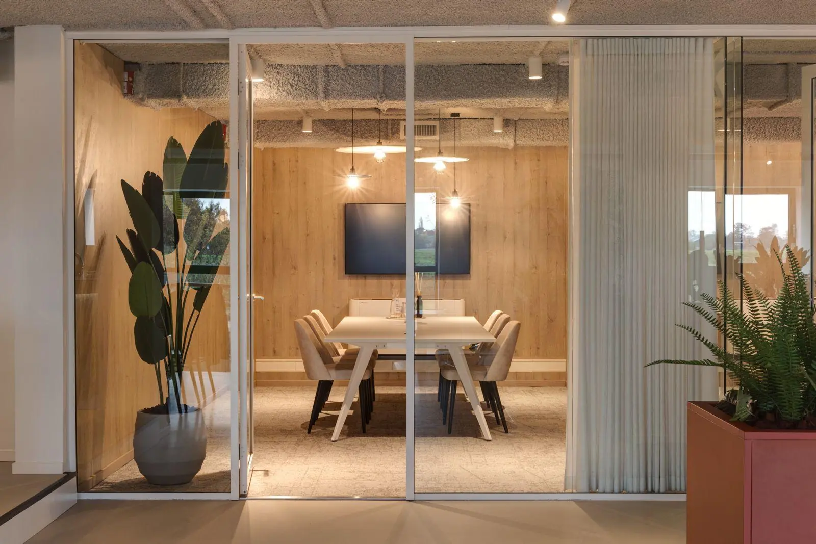 Moderne vergaderruimte met glazen wanden, houten wandafwerking en een grote tafel in het kantoorpand aan de Vanadiumweg 11 in Amersfoort.