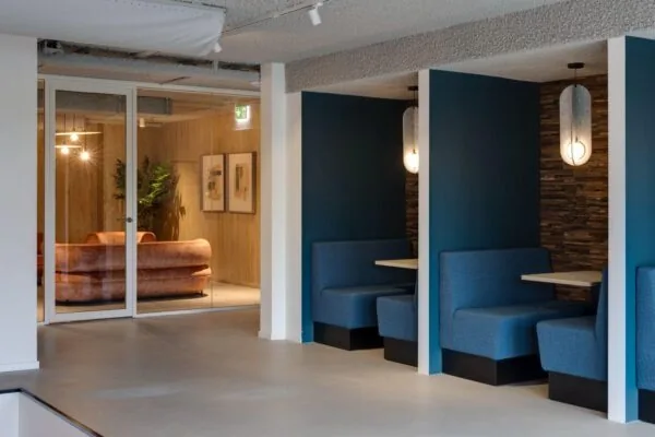 Moderne kantoorruimte aan de Vanadiumweg 11 in Amersfoort met blauwe zithoeken en een glazen vergaderruimte met roze banken.