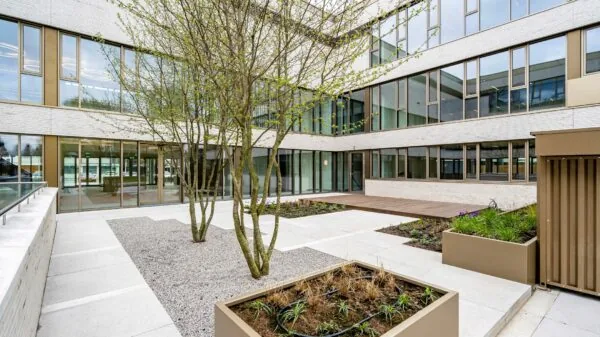 Binnenplaats van kantoorgebouw Walborg 2 in Amsterdam met moderne gevel, grote ramen en groen aangelegde plantenbakken.