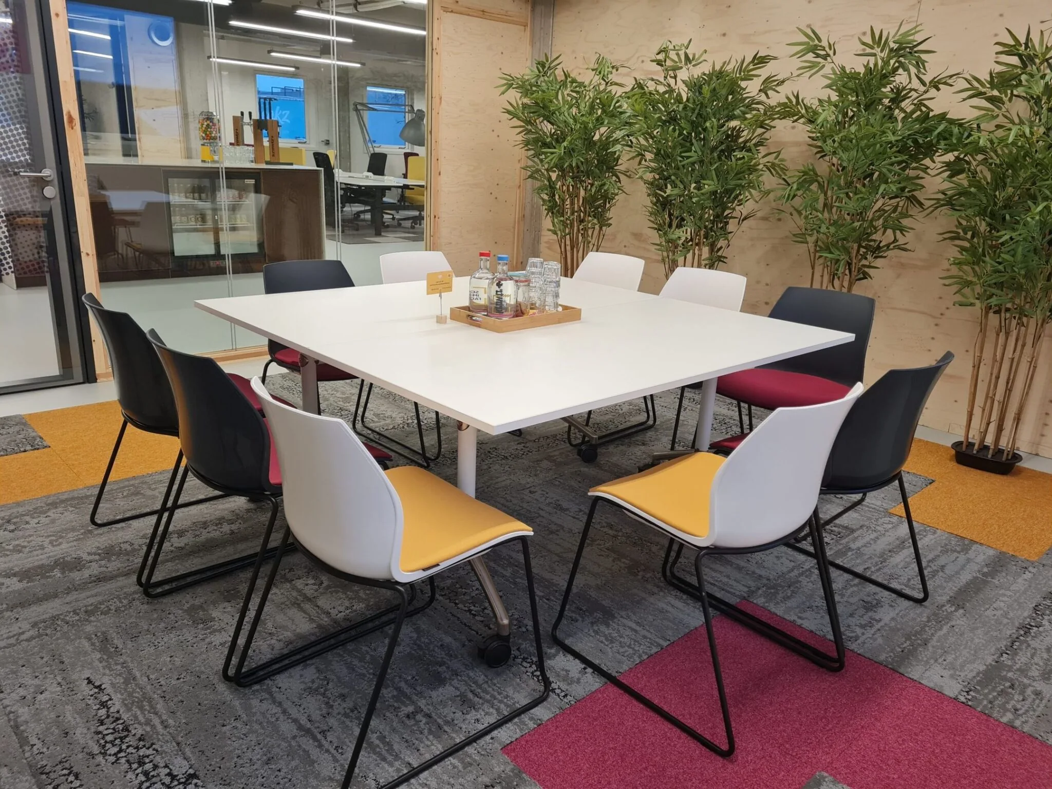 Vergaderruimte met kleurrijke stoelen en een grote tafel in een modern kantoor aan de Willem Fenengastraat 2 in Amsterdam.
