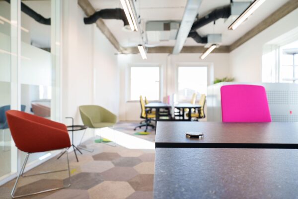 Moderne, lichte kantoorruimte aan de Willem Fenengastraat 2 in Amsterdam met kleurrijke stoelen en open werkplekken.