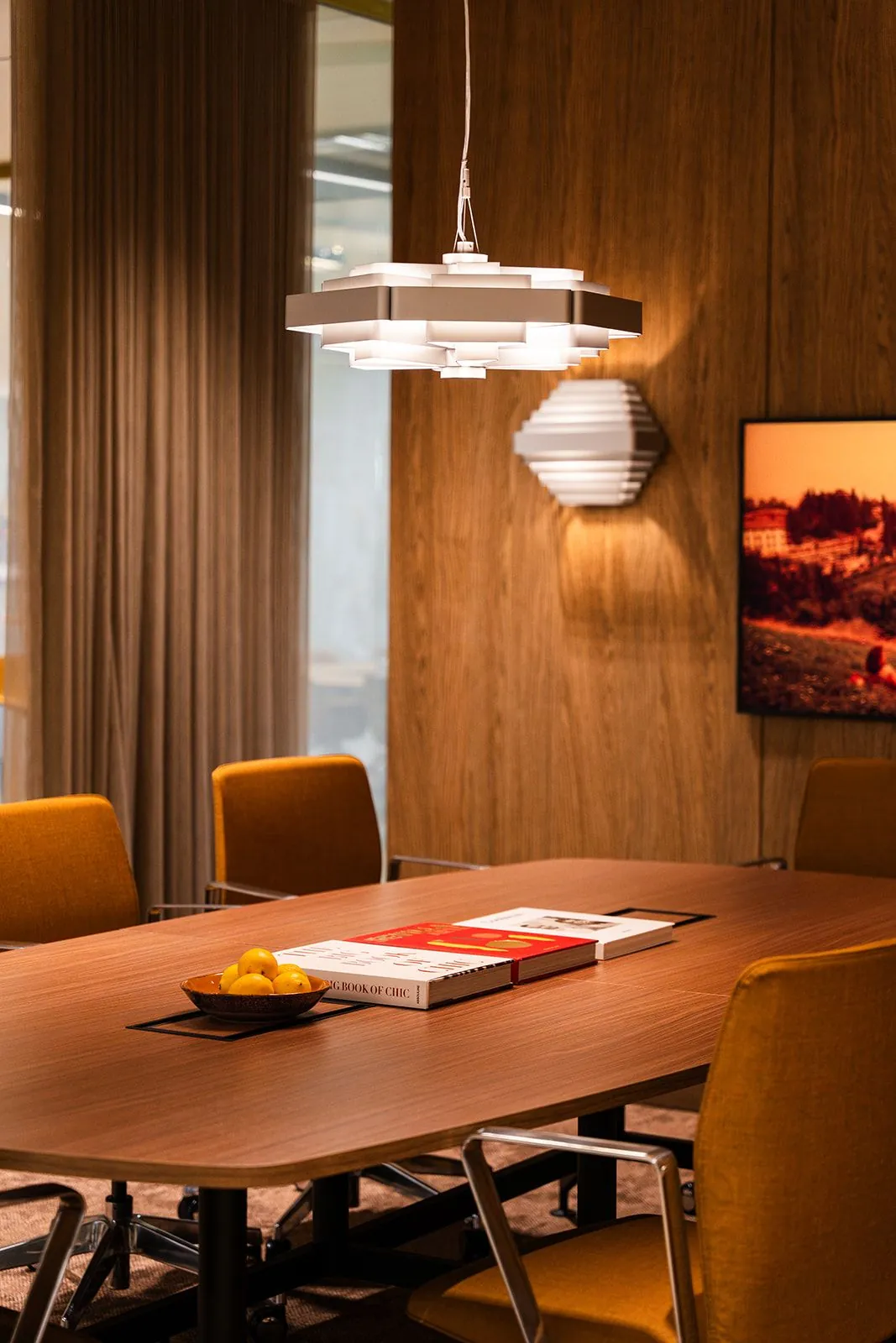 Vergaderruimte met houten tafel, gele stoelen, moderne verlichting en decoratieve accenten aan de Zeestraat 70 in Den Haag.