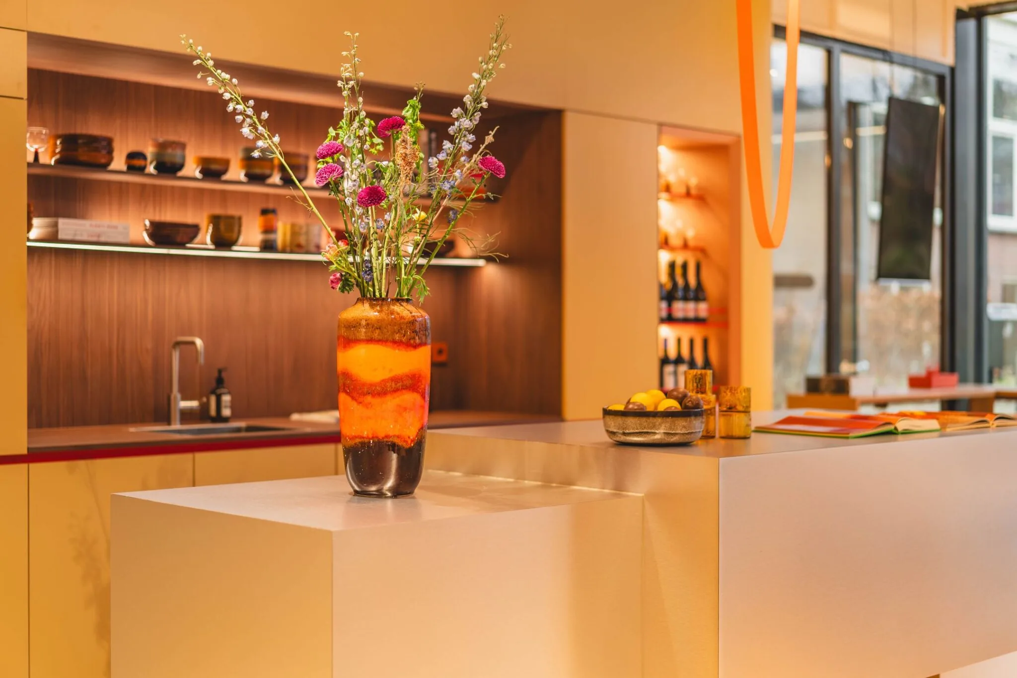 Moderne kantoorruimte aan de Zeestraat 70 in Den Haag met een stijlvolle balie, opvallende vaas met bloemen en warme verlichting.