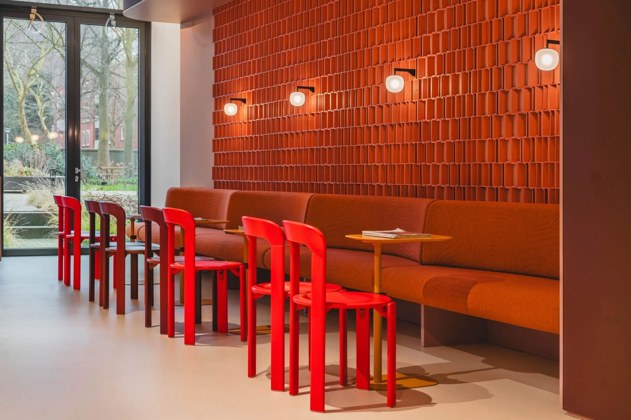 Moderne kantoorruimte aan de Zeestraat 70 in Den Haag met felrode stoelen, oranje wandbanken en een opvallende rode wandbekleding.