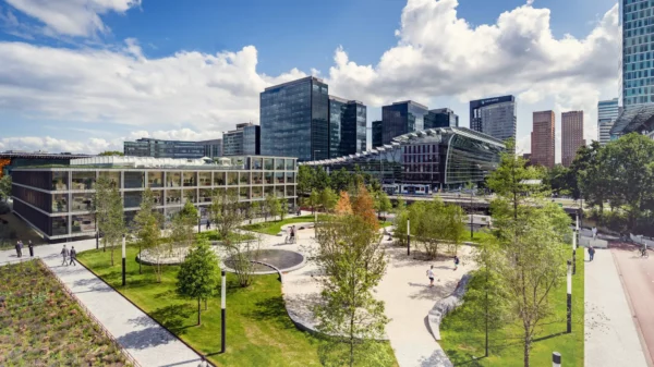 Moderne kantoorgebouwen aan de Strawinskylaan op de Zuidas in Amsterdam met groen park en wandelpaden op de voorgrond.