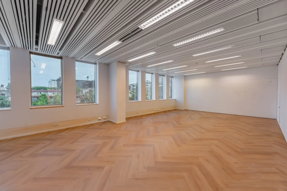Lichte, moderne kantooruimte met visgraatvloer en grote ramen aan de Weesperstraat 107.