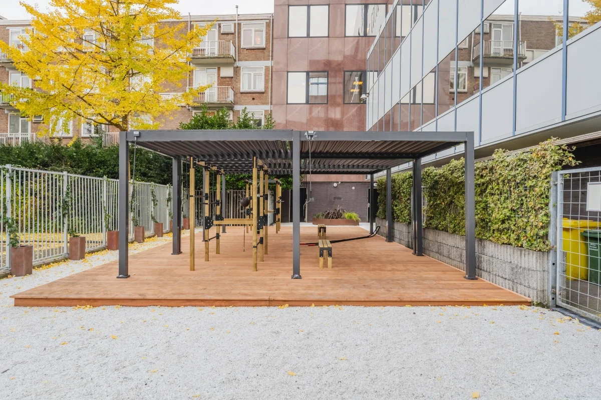 Overdekte buitengym met houten vloer en fitnessapparatuur bij kantoorpand aan de Weesperstraat 107.