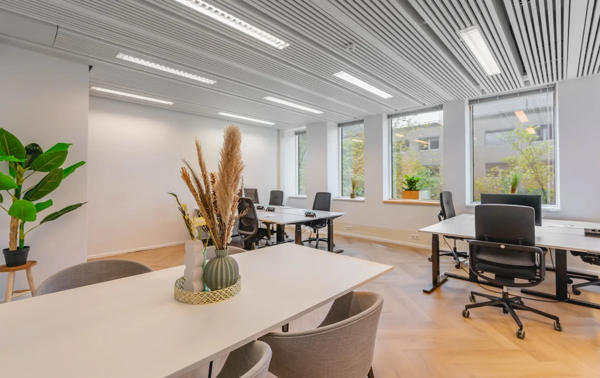 Moderne, lichte kantooruimte aan de Weesperstraat 107 met werkplekken, grote ramen en groene accenten.