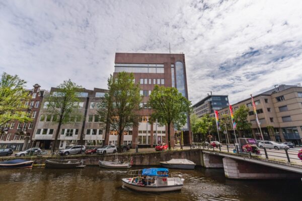 Kantoorpand aan de Weesperstraat 107-133 in Amsterdam met uitzicht op de gracht en passerende bootjes.