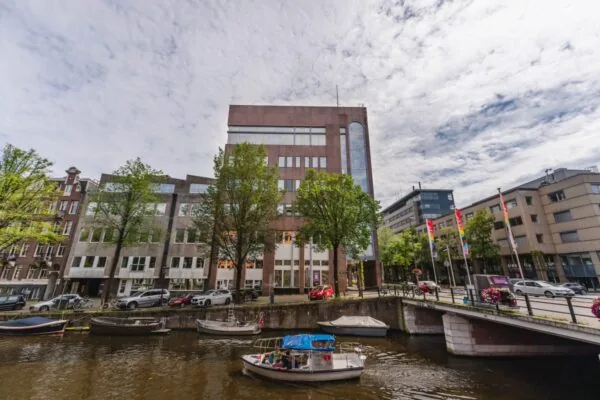 Kantoorpand aan de Weesperstraat 107-133 in Amsterdam met uitzicht op de gracht en passerende bootjes.