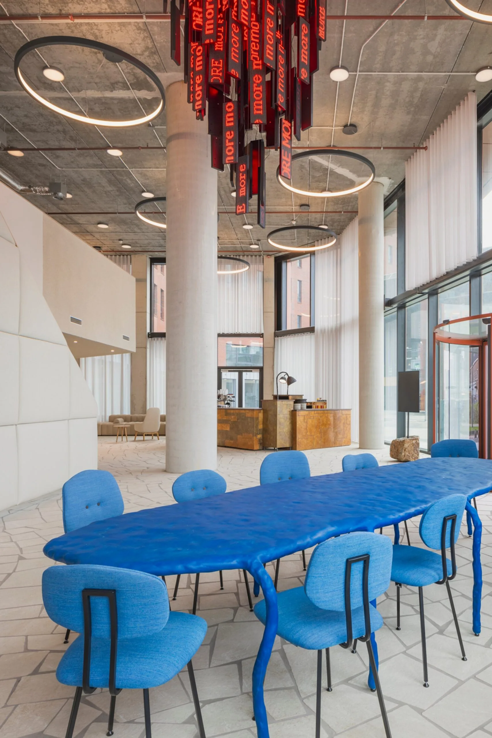 Moderne kantoorlobby aan de HJE Wenckebachweg 230 in Amsterdam met een opvallende blauwe vergadertafel en designinterieur.