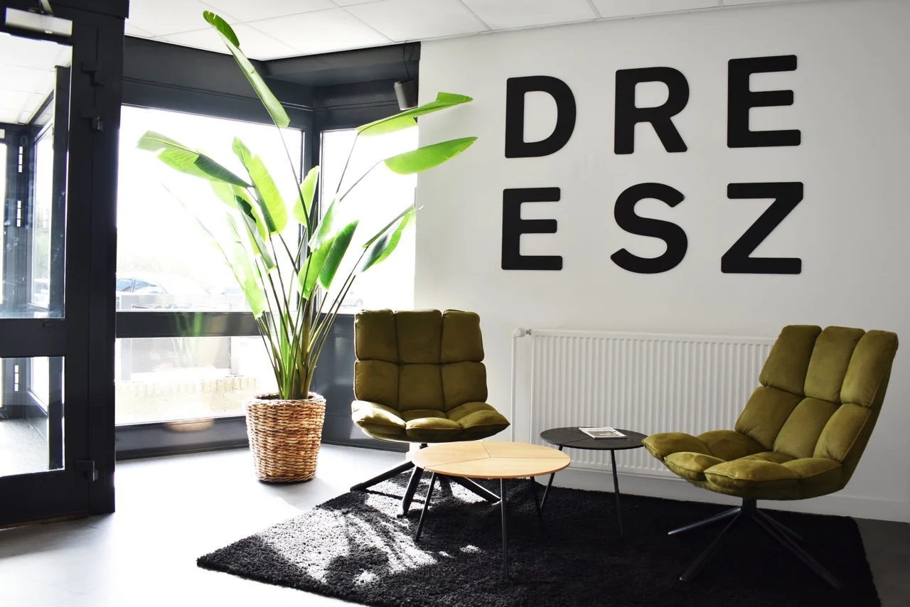 Moderne wachtruimte in kantoorgebouw aan de Keulenstraat 9 in Deventer met groene stoelen, grote plant en muurletters "DREESZ".