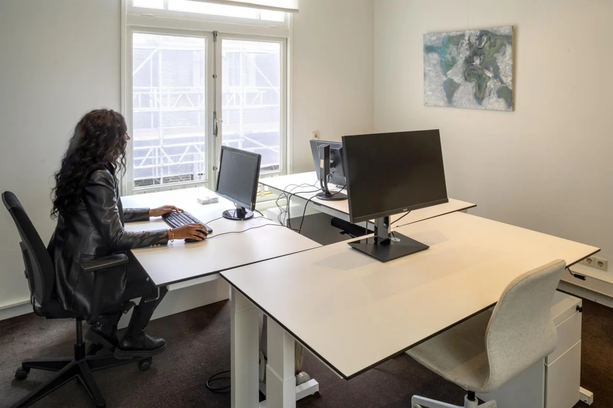 Een vrouw werkt op een computer in een modern kantoor aan de Keizersgracht 106.