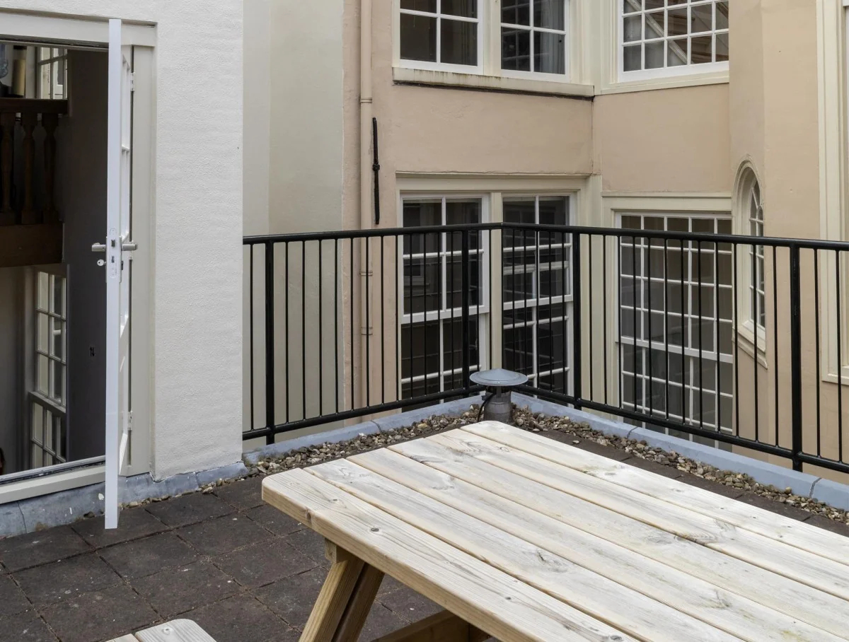 Houten picknicktafel op een dakterras met uitzicht op de binnengevel van Keizersgracht 106.