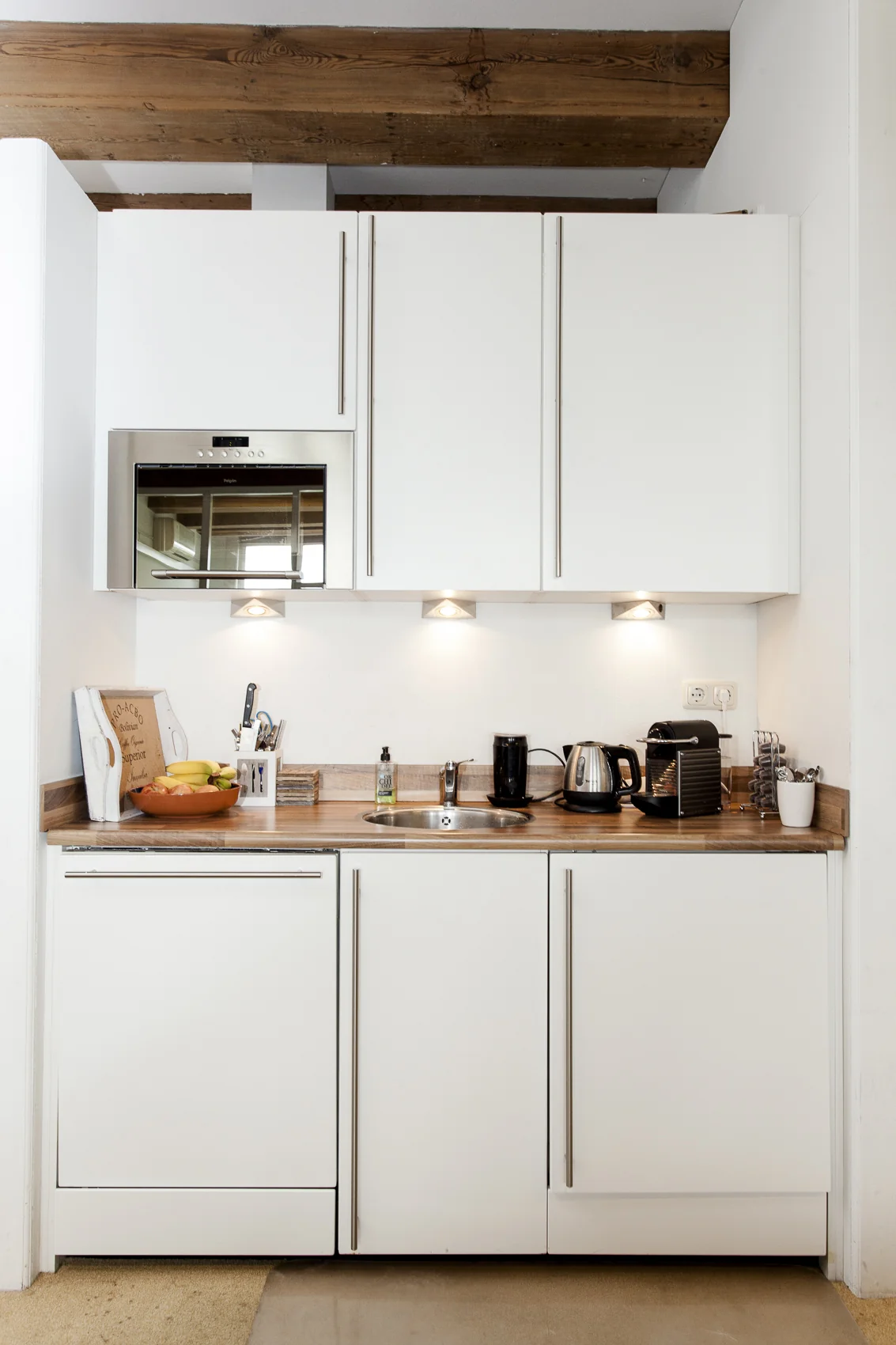 Moderne witte keuken bij Keizersgracht 241 met houten werkblad, inbouwapparatuur en zichtbare plafondbalken.