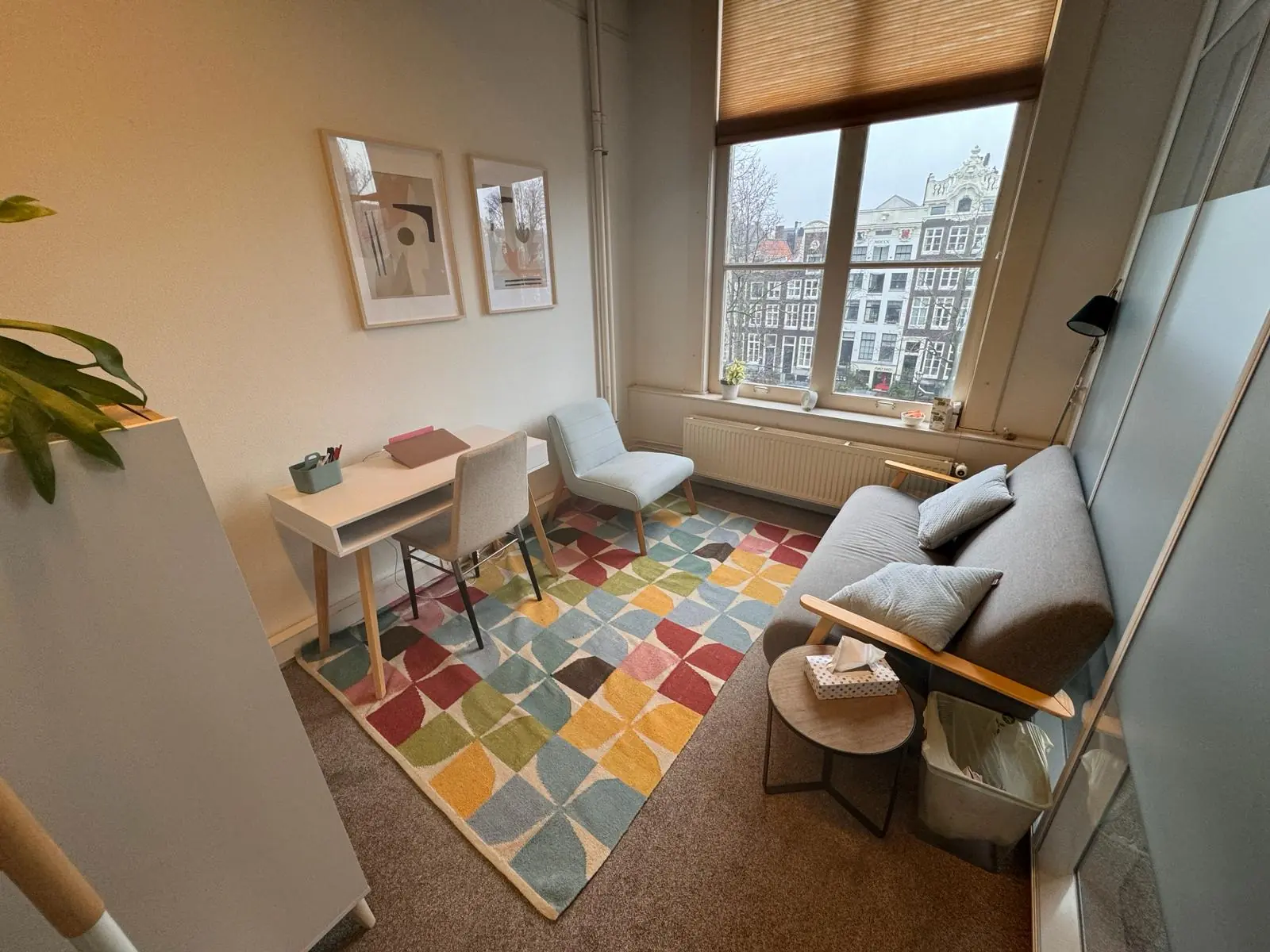 Modern ingerichte werkruimte aan de Keizersgracht 241 met een bureau, zitgedeelte en uitzicht op historische panden.