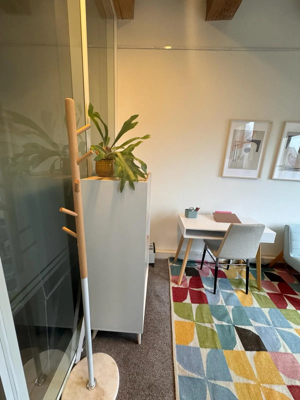 Modern ingericht kantoor aan de Keizersgracht 241 met bureau, kleurrijk vloerkleed, plant en kapstok.