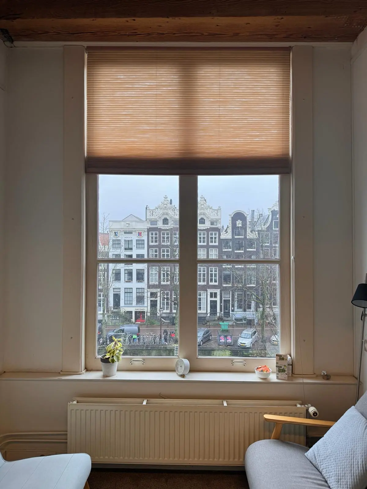 Uitzicht vanuit een woonkamerraam op grachtenpanden aan de Keizersgracht in Amsterdam.