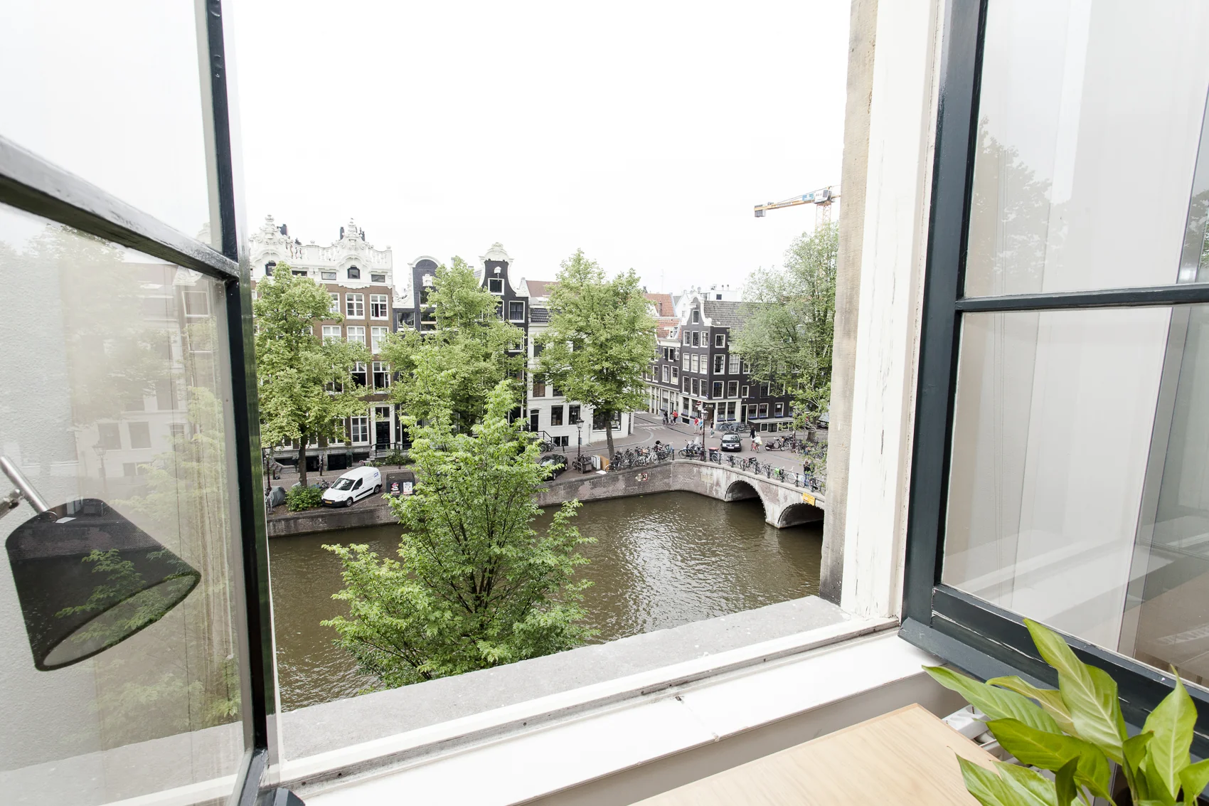 Uitzicht vanuit een vergaderruimte aan de Keizersgracht op een Amsterdamse gracht met monumentale panden en een brug.
