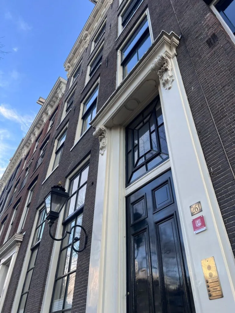 Voorgevel van het pand Keizersgracht 261 in Amsterdam met zwarte deur, klassieke geveldetails en huisnummerbordje.