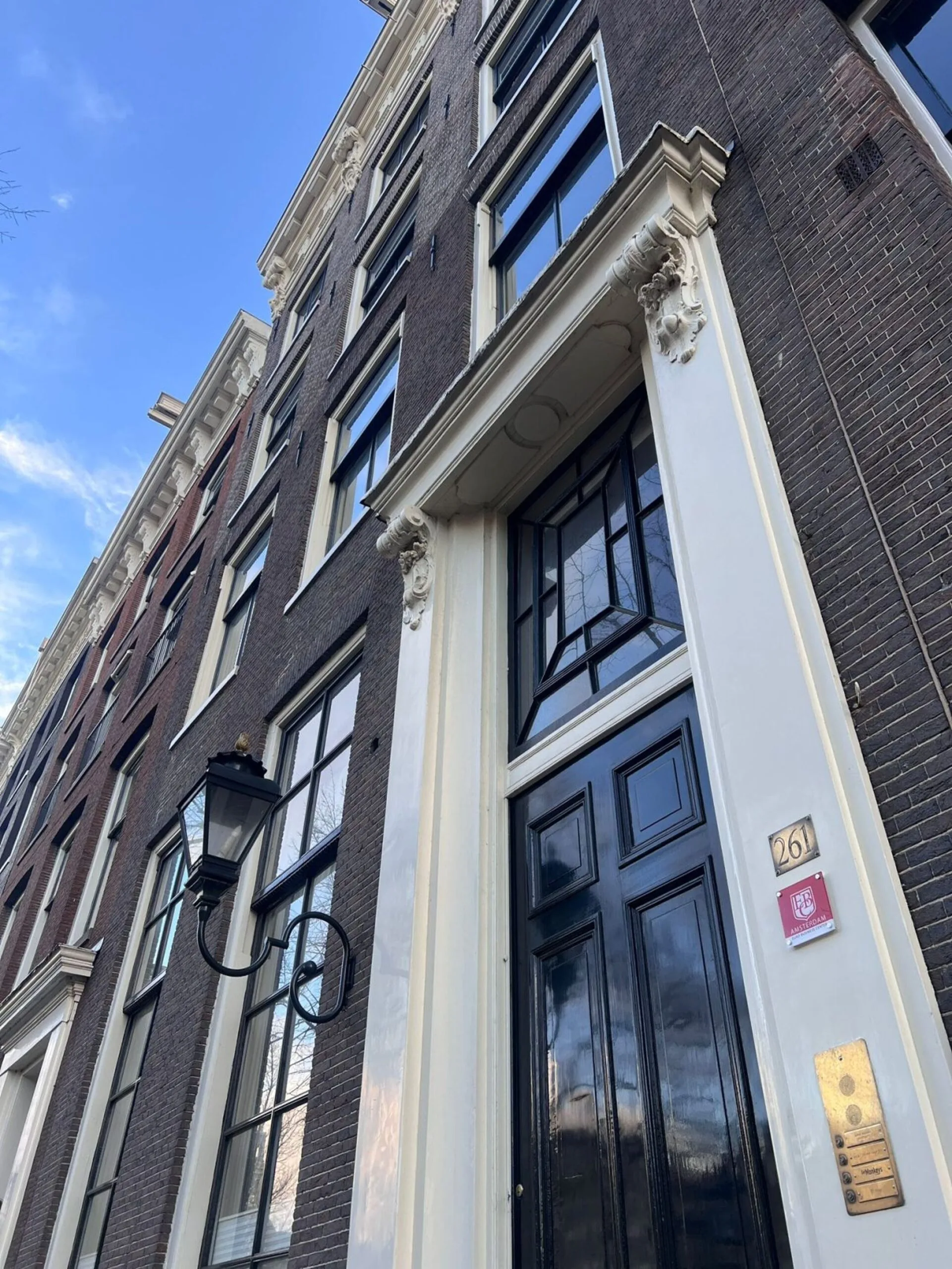 Voorgevel van het pand Keizersgracht 261 in Amsterdam met zwarte deur, klassieke geveldetails en huisnummerbordje.