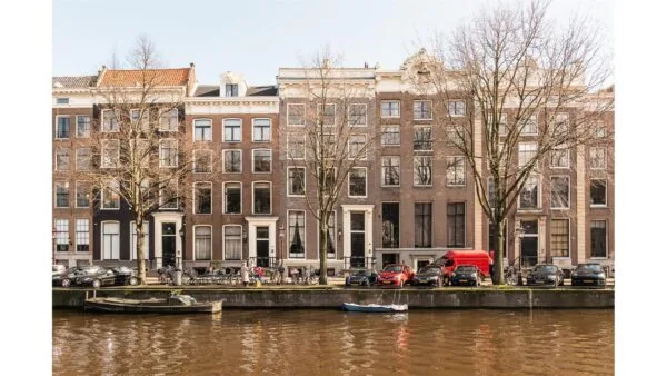 Gevelaanzicht van Keizersgracht 261 in Amsterdam met grachtenpand, geparkeerde auto's en boten in de gracht.