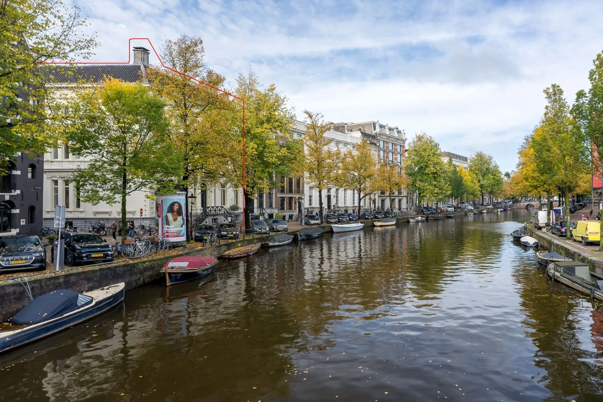 Uitzicht op Keizersgracht 452 in Amsterdam met grachtenpand, geparkeerde auto's en bootjes aan de kade.