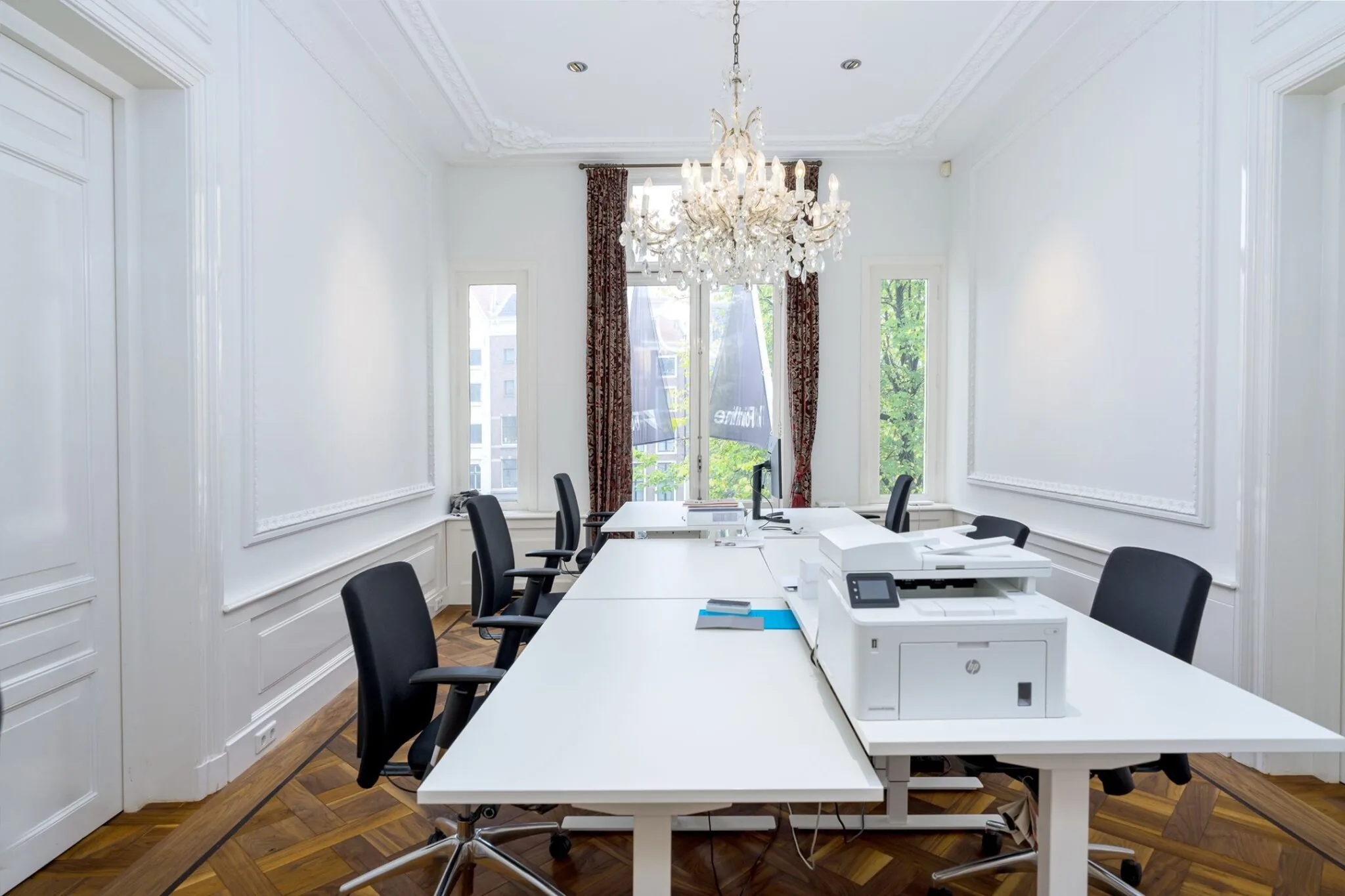 Stijlvol ingericht kantoor aan de Keizersgracht 452 met moderne werkplekken, kroonluchter en grote ramen met uitzicht op de gracht.