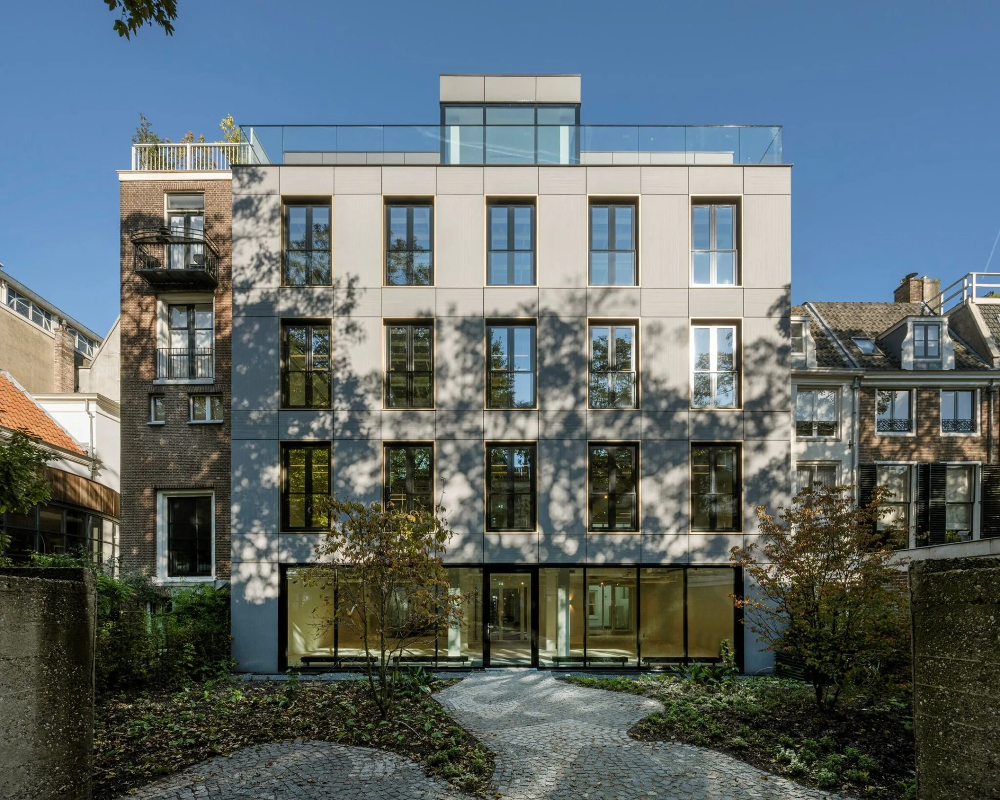 Modern woongebouw aan de Keizersgracht 572 met grote ramen en een betegeld tuinpad op de voorgrond.