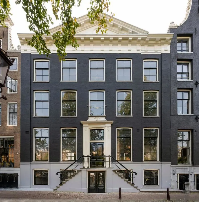Voorgevel van het monumentale pand Keizersgracht 572 in Amsterdam met zwarte gevel, symmetrische ramen en een witte entree met trap.