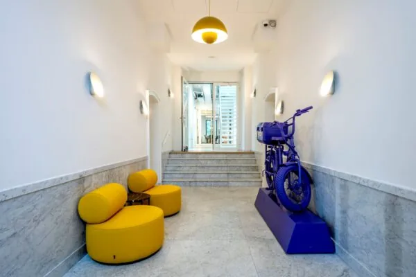 Moderne entreehal van Keizersgracht 572 met gele zitmeubels en een paars kunstwerk van een motorfiets.