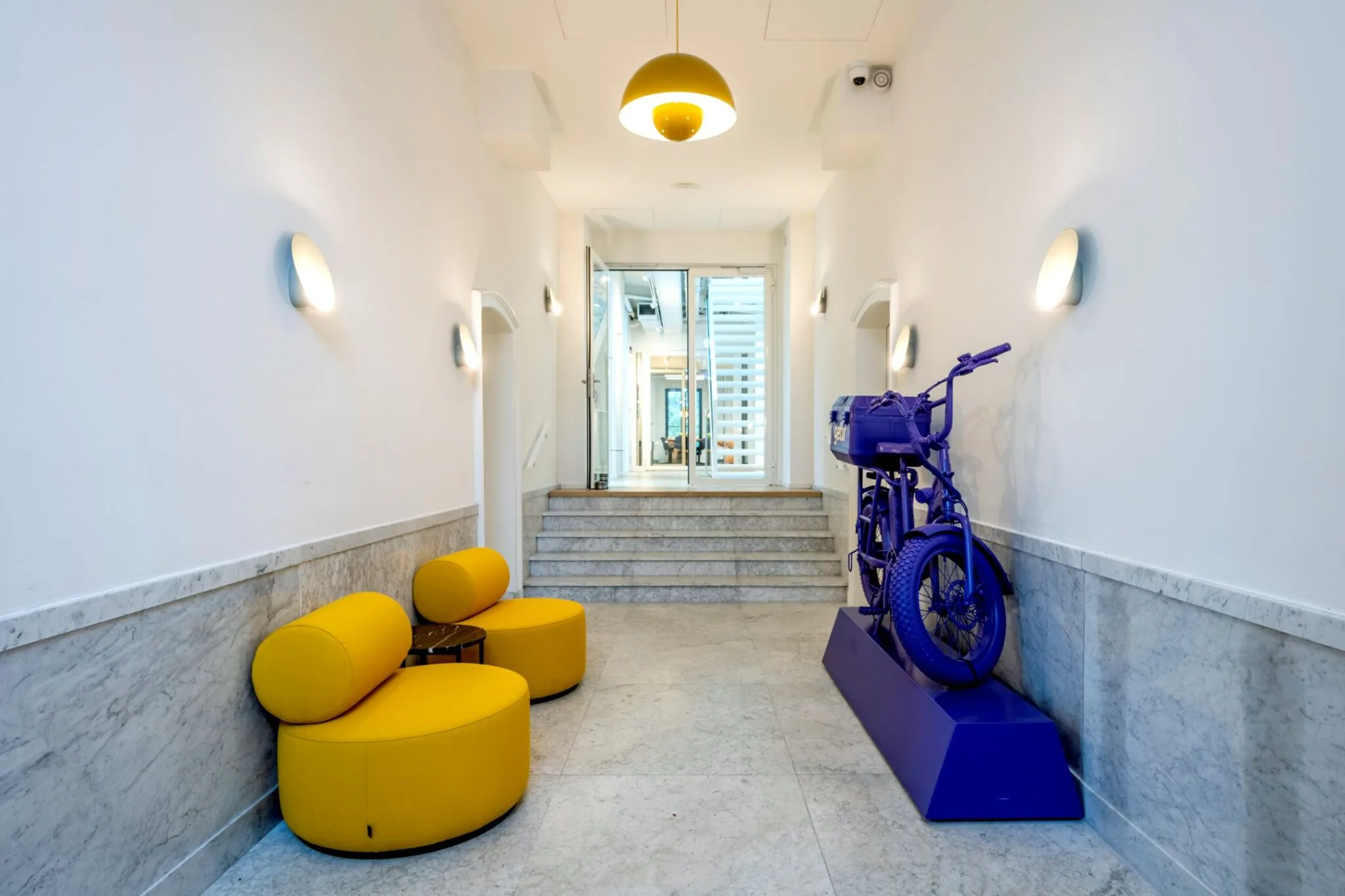 Moderne entreehal van Keizersgracht 572 met gele zitmeubels en een paars kunstwerk van een motorfiets.