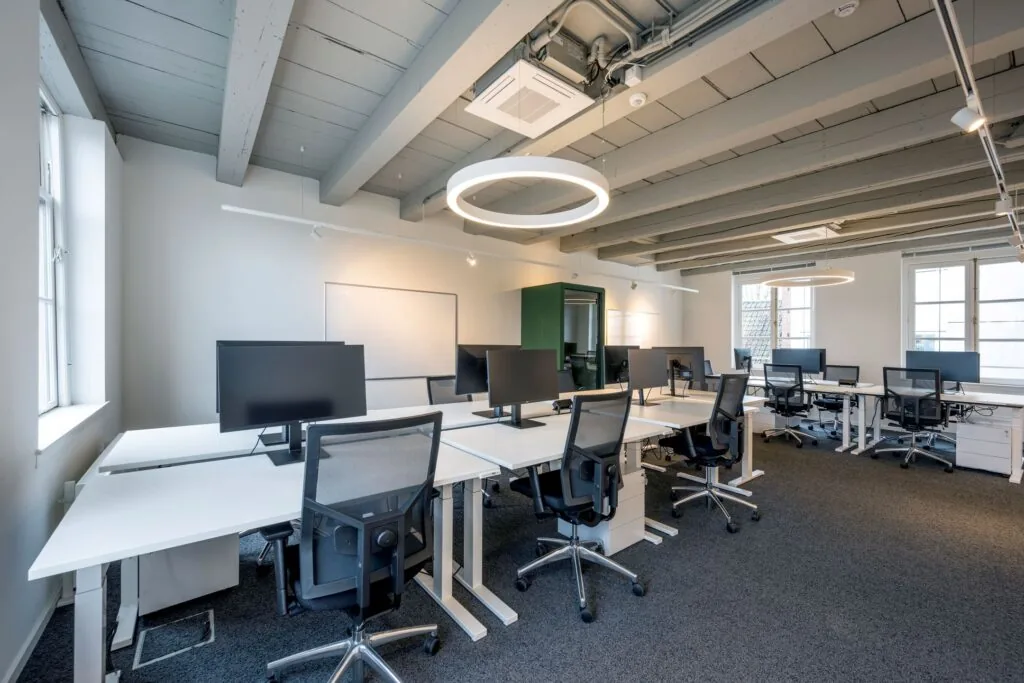 Modern ingerichte kantoorruimte op Keizersgracht 572 met meerdere werkplekken, bureaustoelen en grote bureaulampen.