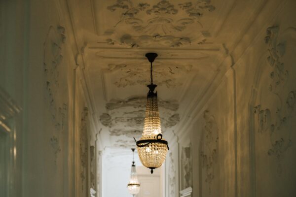 Sierlijke gang met kroonluchters en rijk gedecoreerd stucwerk aan het plafond in Keizersgracht 64.