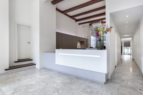 Moderne receptiebalie met bloemenvaas in een strak wit interieur aan de Keizersgracht 64.