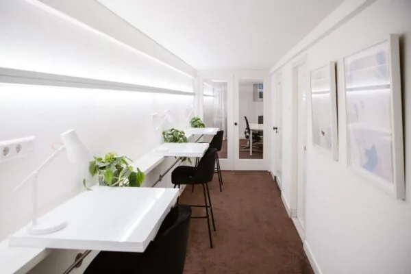 Lichte, moderne werkruimte met witte bureaus, zwarte stoelen en kamerplanten in Keizersgracht 64.