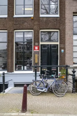 Twee fietsen staan geparkeerd voor de ingang van het pand aan de Keizersgracht 97 in Amsterdam.