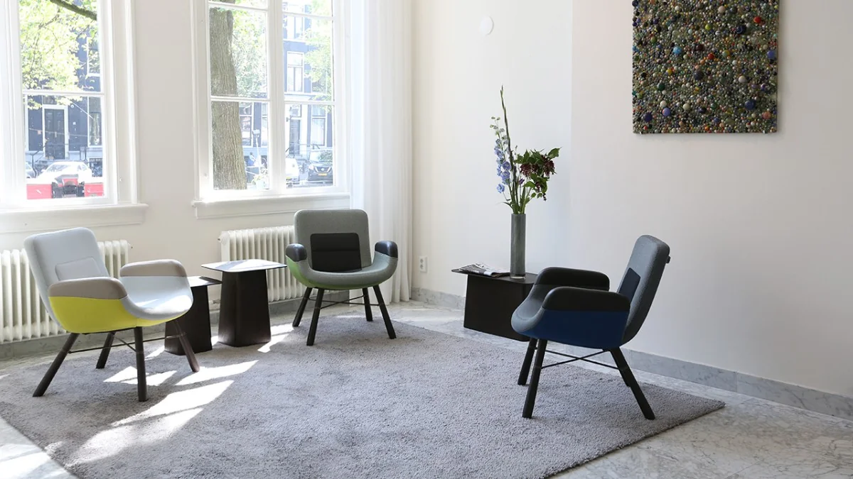 Moderne wachtruimte in Keizersgracht 97 met designstoelen, kunst aan de muur en grote ramen met uitzicht op de gracht.