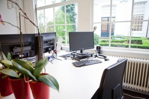 Modern kantoor bij Keizersgracht 97 met werkplekken en uitzicht op een groene binnentuin.